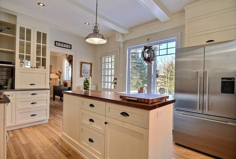 Cuisine lumineuse au style classique avec armoires blanches par 3D ID Design Cuisine lumineuse au style classique avec armoires blanches, comptoir en bois et électroménagers en acier inoxydable par 3D ID Design