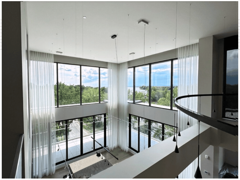 Salle de séjour moderne avec baies vitrées et habillage de fenêtres motorisé installé par Alliance Domotique Design