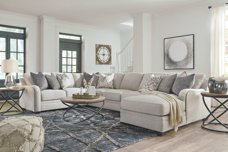Salon Moderne Avec un Canapé Sectionnel Beige Salon moderne avec un canapé sectionnel beige, table basse ronde en bois et métal, tapis texturé gris, et décor élégant comprenant des coussins, une horloge murale et une œuvre d'art.