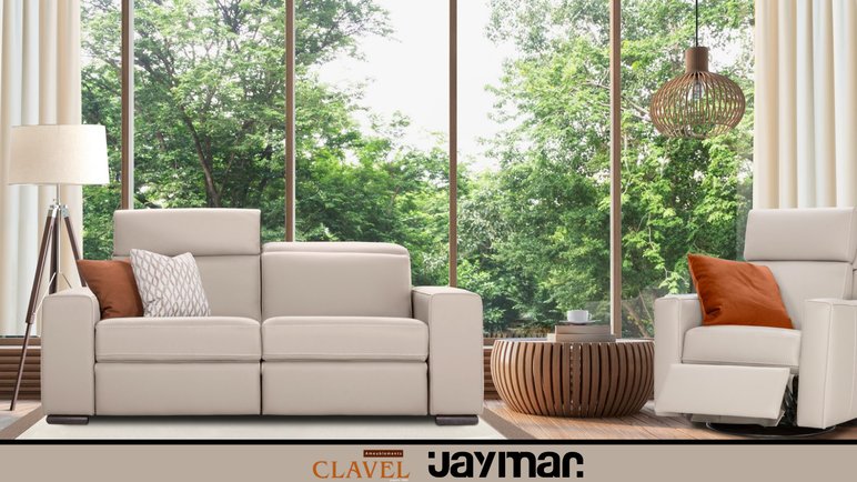 Salon moderne avec canapé et fauteuil inclinable Jaymar en cuir beige, décoré de coussins, devant une grande baie vitrée avec vue sur des arbres, chez Ameublements Clavel