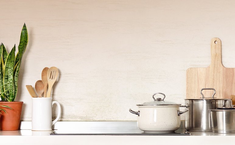 Articles de Cuisine par Doyon Després Ustensiles de cuisine en bois, casseroles en acier inoxydable et cocotte émaillée sur un plan de travail moderne, à côté d'une plante décorative par Doyon Després