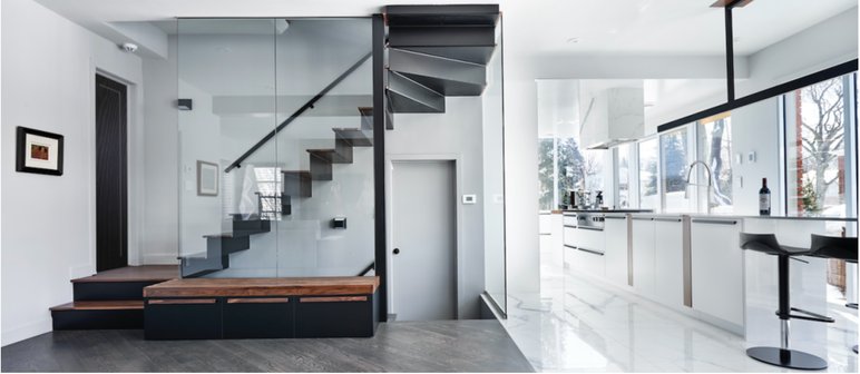 Réalisation de Ferland | Drouin - Escalier moderne en métal et bois dans un espace intérieur épuré et lumineux Escalier contemporain en métal noir et marches en bois, entouré de parois en verre, dans une maison lumineuse avec une cuisine ouverte et un design minimaliste. Lien vers site web de Ferland | Drouin