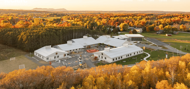 Vue aérienne d’un établissement scolaire conçu par Leclerc Architectes Vue aérienne d’un établissement scolaire conçu par Leclerc Architectes, intégré à un paysage forestier aux couleurs d’automne