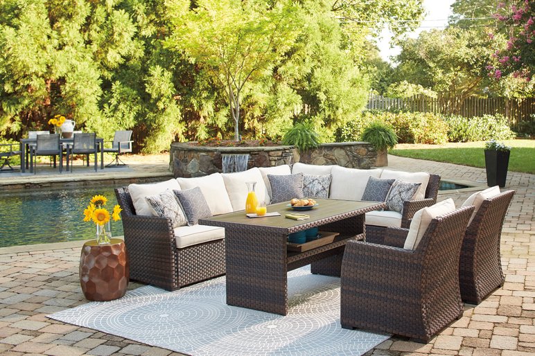 Espace Extérieur Aménagé Avec un Salon de Jardin en Résine Tressée de Chez Ameublements Boulet Espace extérieur aménagé avec un salon de jardin en résine tressée, coussins beiges et table basse, au bord d'une piscine entourée de verdure de chez Ameublements Boulet
