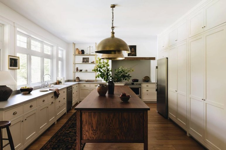 Cuisine élégante au style farmhouse chic avec îlot en bois massif de chez Cuisines Rochon Cuisine lumineuse au design farmhouse chic avec un grand îlot en bois, des armoires blanches classiques, un luminaire en laiton et de grandes fenêtres laissant entrer la lumière naturelle de chez Cuisines Rochon