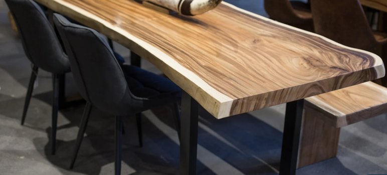 Table en Bois Massif avec Chaises en Velours Noir Table en bois massif avec bordure naturelle, pieds en métal noir et chaises en velours noir, dans un intérieur moderne