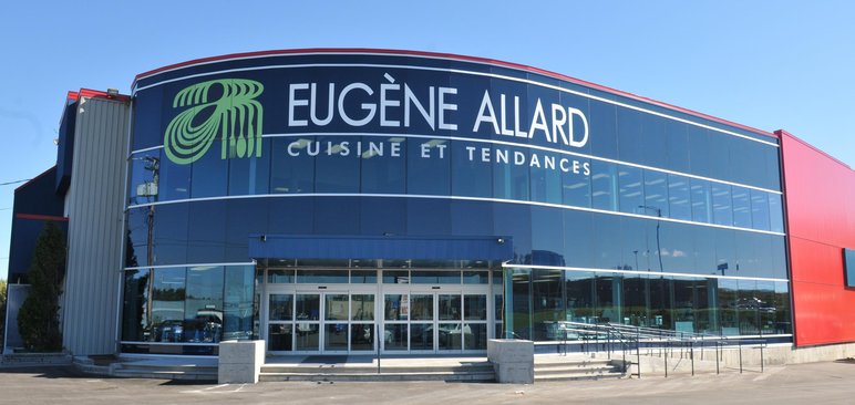 Façade vitrée du magasin Eugène Allard Cuisine et Tendances Façade vitrée du magasin Eugène Allard Cuisine et Tendances, avec logo vert stylisé d'ustensiles de cuisine, au Québec