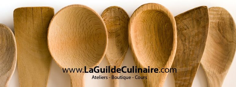 Cuillères en bois artisanales alignées de La Guilde Culinaire Cuillères en bois artisanales alignées avec le logo de La Guilde Culinaire – Ateliers, Boutique et Cours de cuisine à Montréal