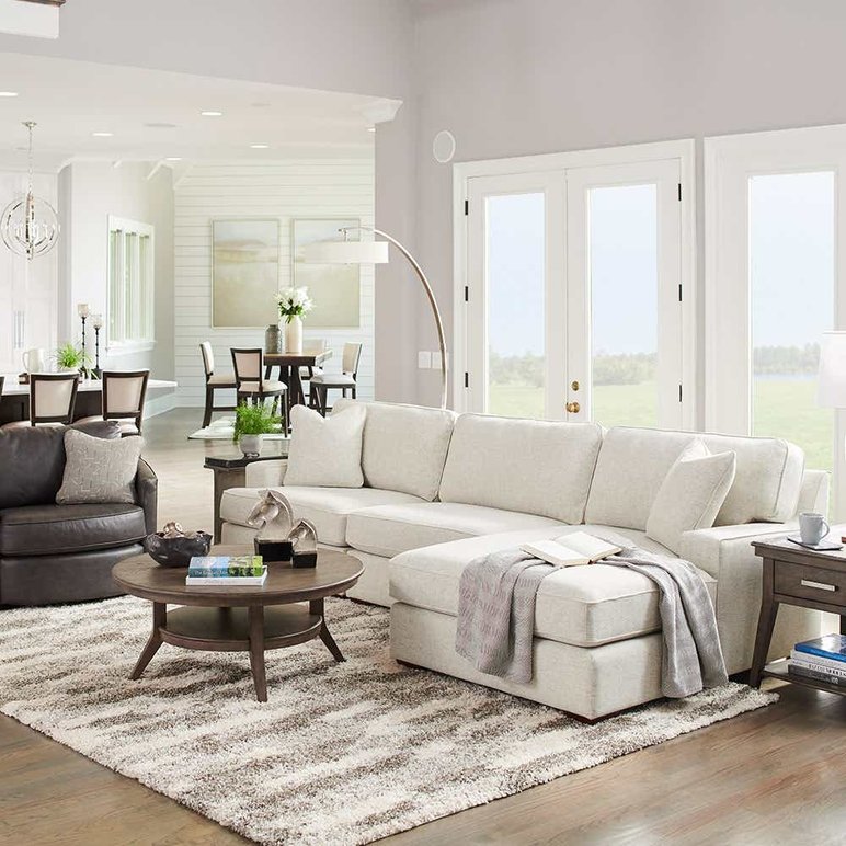 Salon Lumineux Avec un Grand Canapé Sectionnel Beige de Chez Meubles La-Z-Boy Salon lumineux avec un grand canapé sectionnel beige, fauteuil en cuir noir, table basse en bois et tapis moelleux, dans une ambiance chaleureuse et moderne de chez Meubles La-Z-Boy