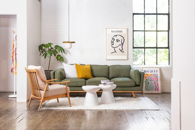 Salon lumineux au style moderne et minimaliste avec un canapé vert de chez Zone Maison Salon lumineux au style moderne et minimaliste avec un canapé vert, un fauteuil en bois, une table basse blanche et une décoration murale artistique de chez Zone Maison