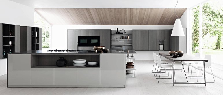 Cuisine moderne minimaliste avec îlot central et vue sur la nature de Chez PURE Cuisines Cuisine contemporaine au design minimaliste avec un îlot central en finition gris et bois. Espace lumineux avec une grande table à manger, des armoires intégrées et une large baie vitrée donnant sur un jardin verdoyant réalisé par PURE Cuisines