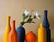 Collection de vases décoratifs en céramique aux teintes orange, jaune et bleu marine, avec fleurs blanches artificielles, sur fond beige - Benigna Nunes Pinterest