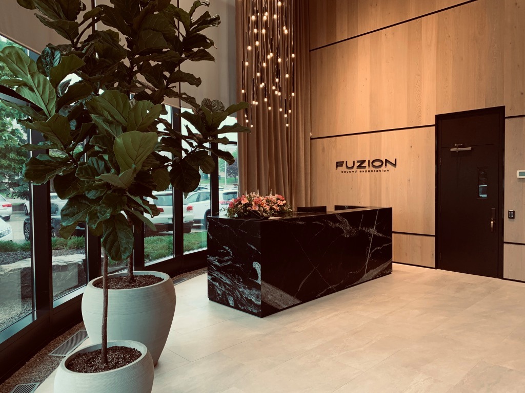 Hall d'entrée moderne de Fuzion Flooring Hall d'entrée moderne de Fuzion Flooring avec un comptoir en marbre noir, un mur en bois clair et des luminaires suspendus design