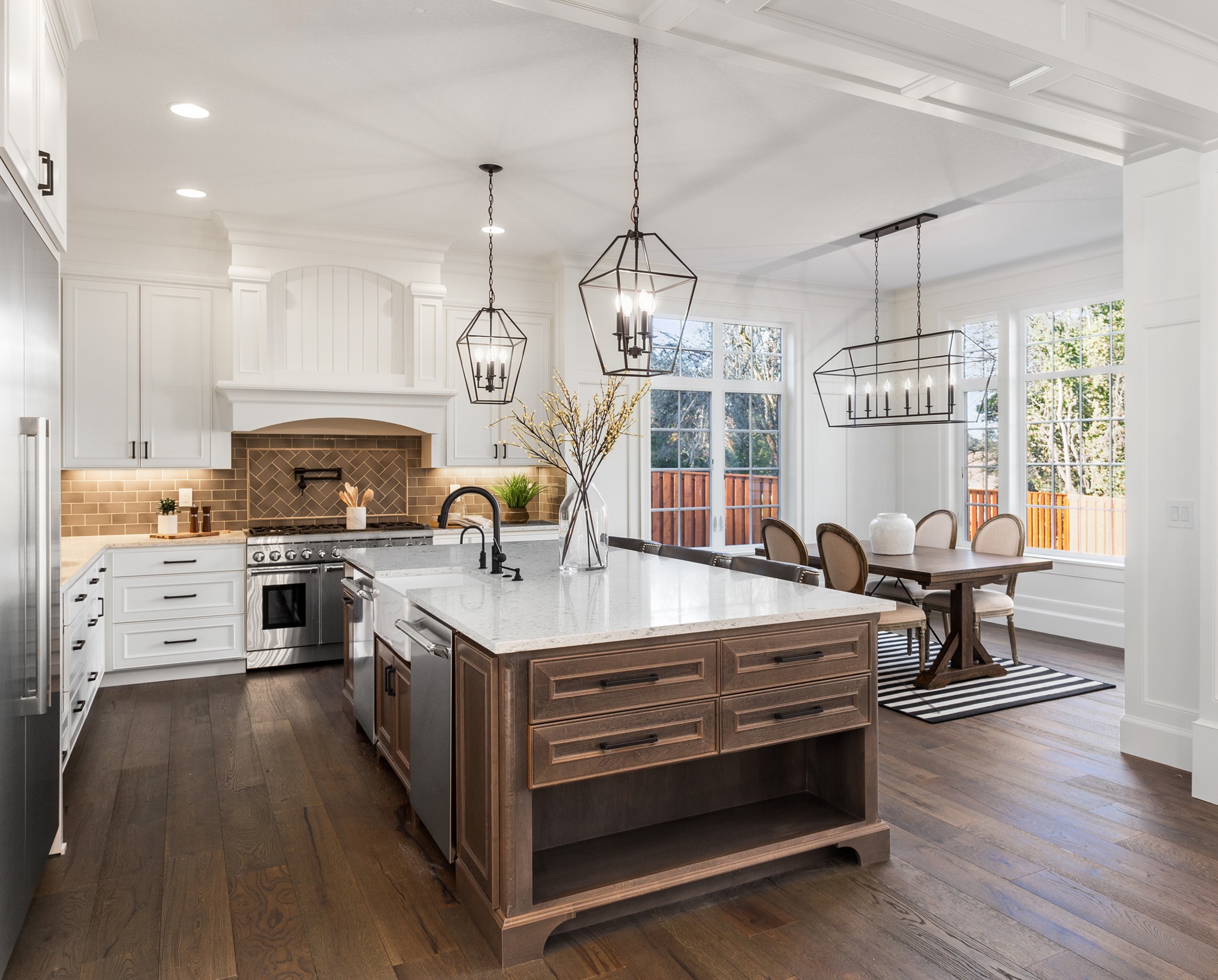 Cuisine haut de gamme moderne – réalisation par RenoVilla Cuisine haut de gamme moderne avec îlot central en bois foncé, armoires blanches et luminaires suspendus – réalisation par RenoVilla