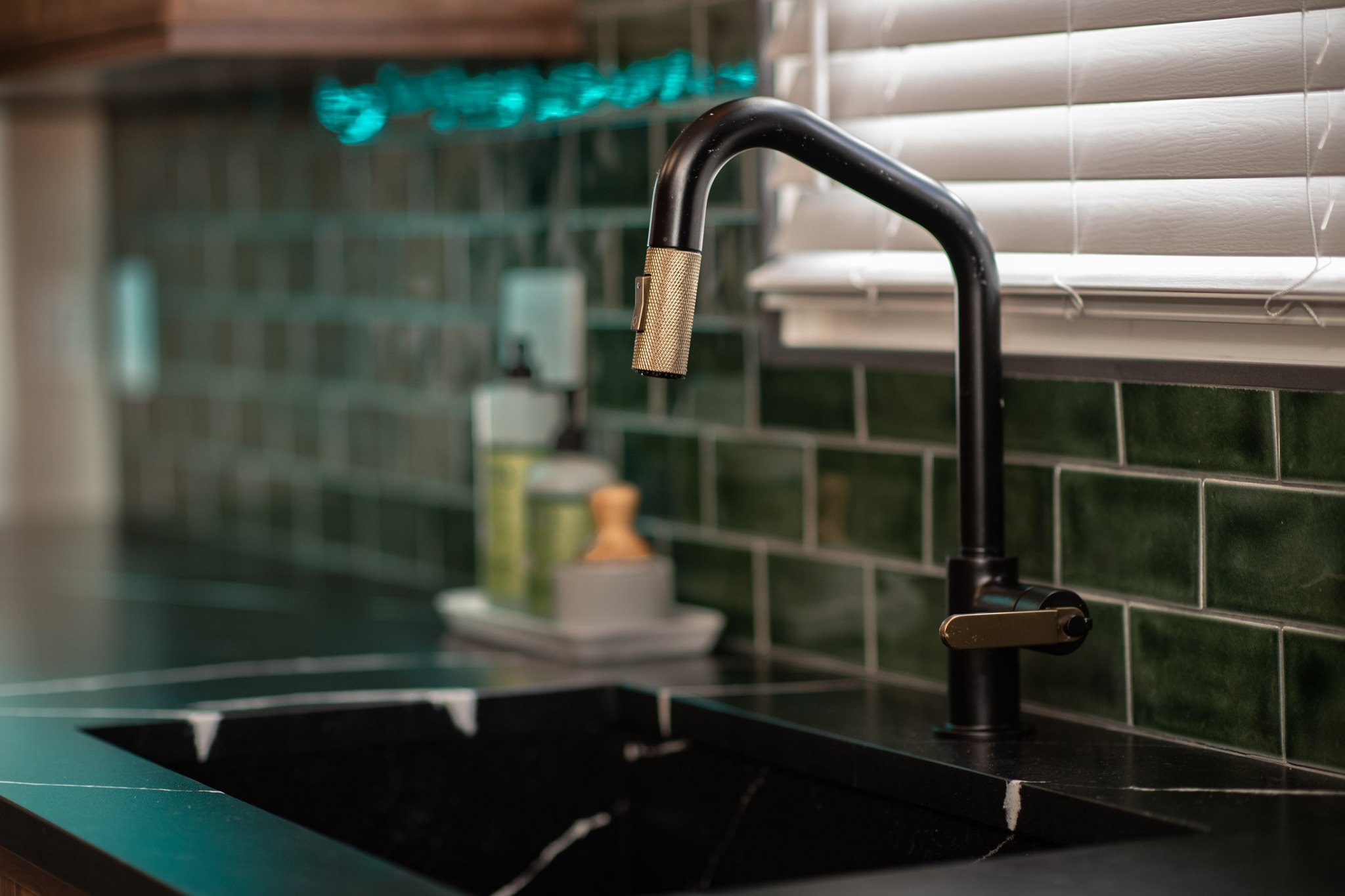 Robinet de cuisine noir mat — design haut de gamme Brizo Robinet de cuisine noir mat avec fini doré brossé, installé sur comptoir en pierre noire avec dosseret en céramique verte — design haut de gamme Brizo